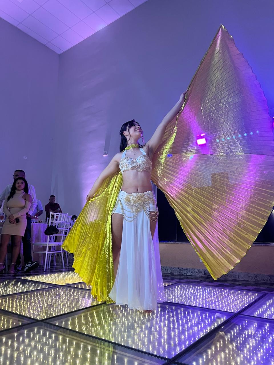 Bailarina com asas douradas em apresentação de dança do ventre